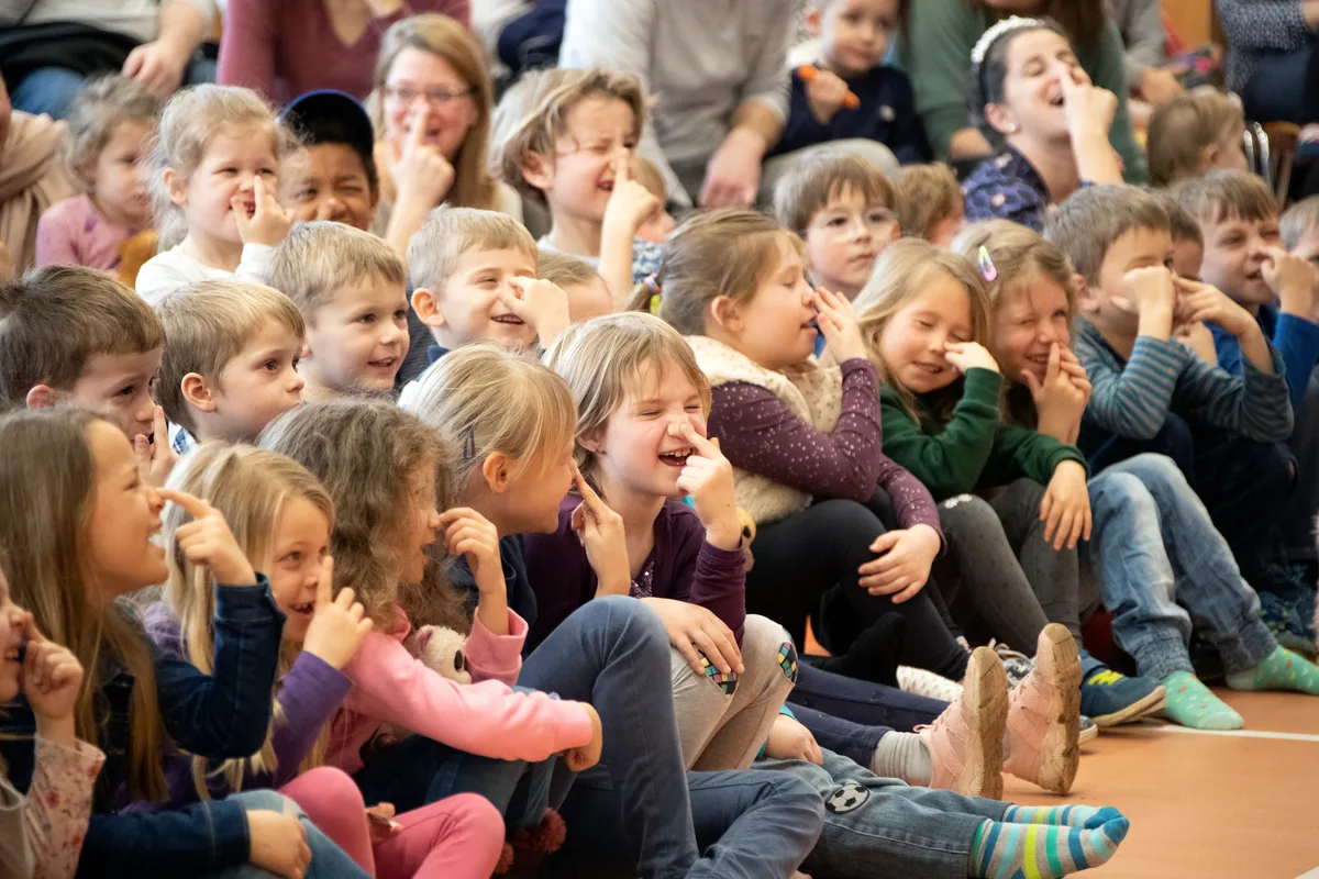 Man sieht mehrere Kinder am Boden sitzen.